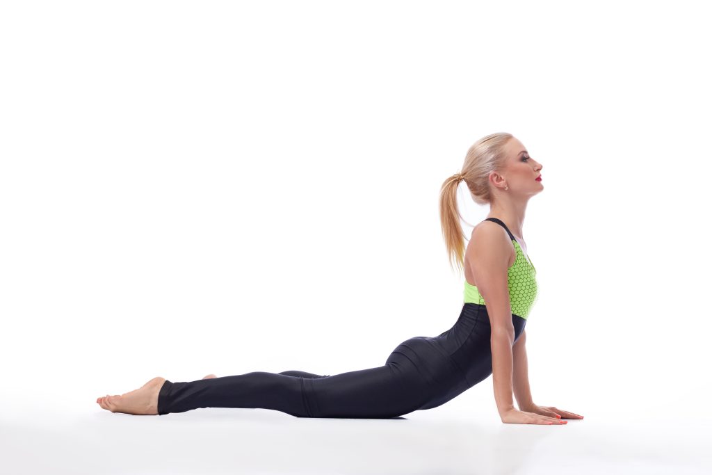 A woman stretching her back at the studio while doing the cobra pose 