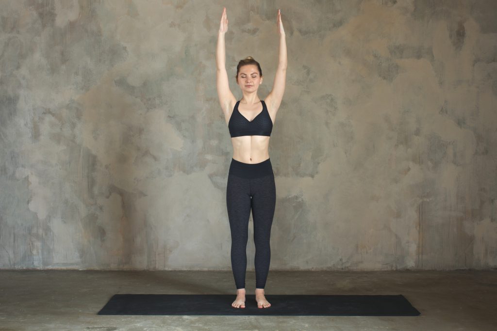 Young woman practicing yoga Mountain pose, urban background