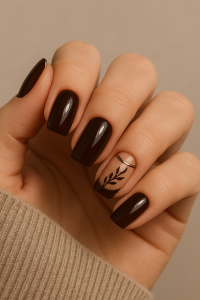 A close-up of a woman’s hand with Chestnut Espresso Brown nail polish, featuring a glossy finish and delicate black leaf nail art details - easy winter nail