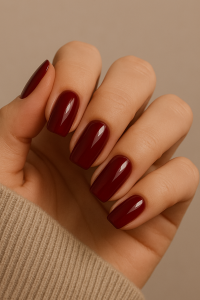 A close-up of a woman’s hand with Wine cherry red nail polish, featuring a glossy finish. - easy winter nail