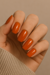 A woman’s hands with pumpkin orange nail polish - easy winter nail 