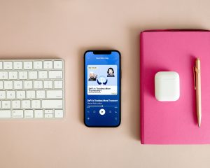 Smartphone playing one of the best motivational podcasts on a minimalist desk setup, creating a calm and inspiring atmosphere for mindful listening.