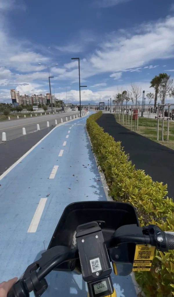 Cycling and biking on a blue coastal bike lane in Antalya with sea views, palm trees, and city buildings under a bright sky.