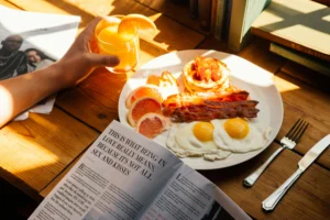 High-Protein Breakfast: 10 Best Ideas for Powerful Mornings Alt text: High-protein breakfast with fried eggs, crispy bacon, pancakes topped with strawberries, fresh grapefruit slices, and a glass of orange juice on a wooden table.