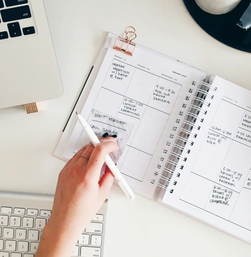 How to Make Time Management for Everything: The 3-Task Rule That Actually Works Woman writing tasks in a weekly agenda notebook as a daily planning and time management strategy to stay productive.